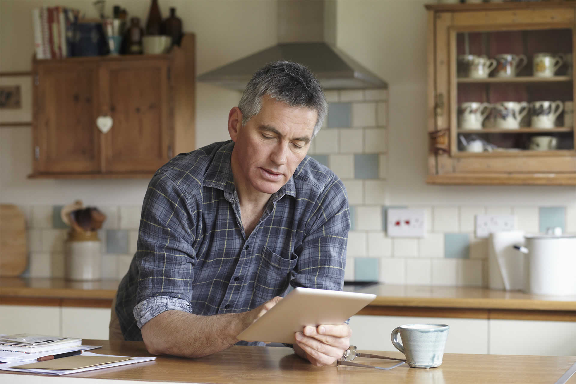 Illustrative picture of a man reviewing his pension from a tablet at home